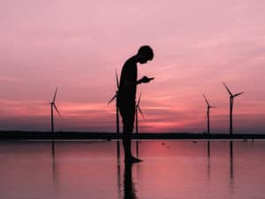 Man with mobile phone in front of wind turbines